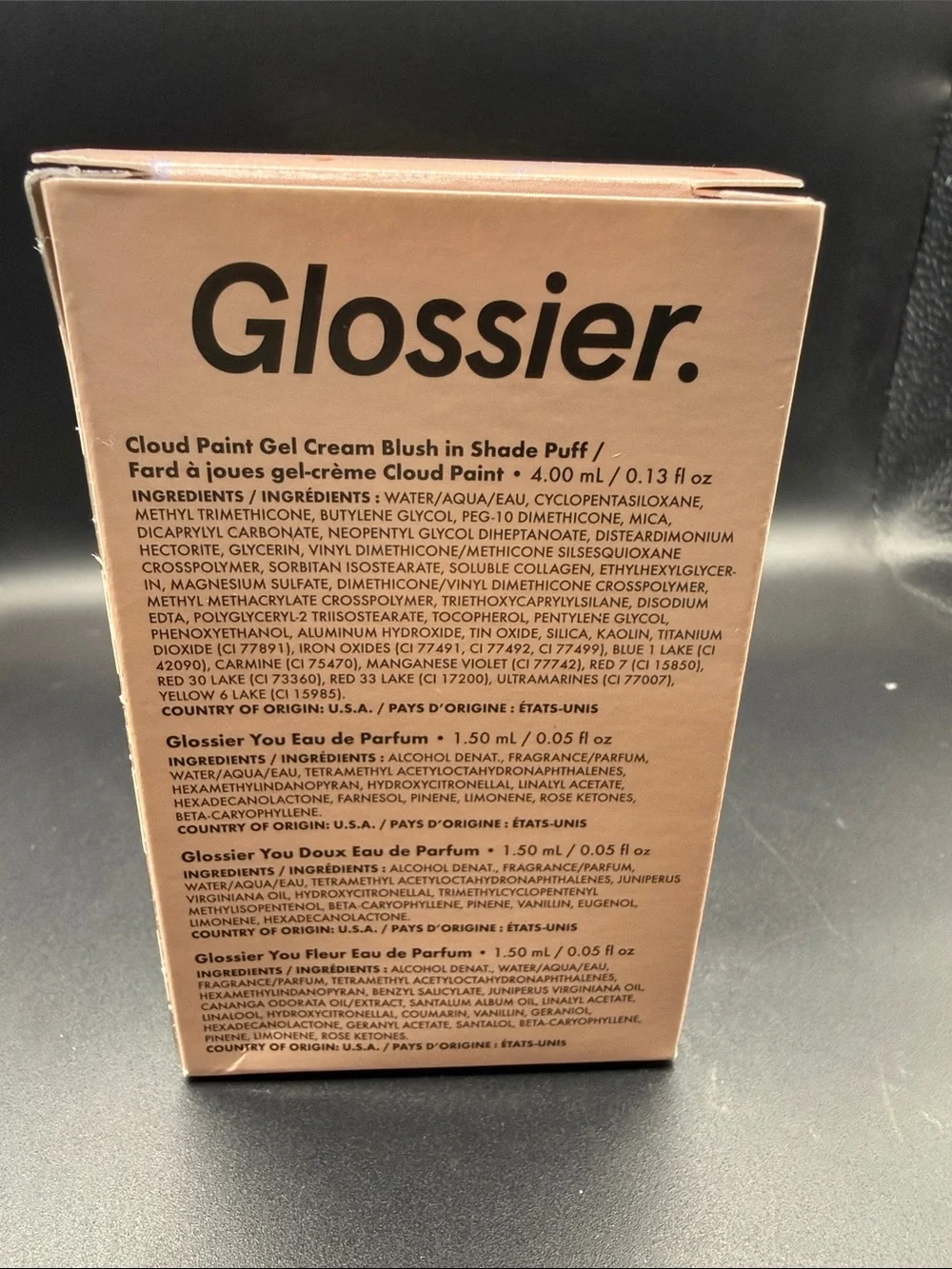 Glossier mini Cloud Paint blush in Puff alongside three mini fragrance samples